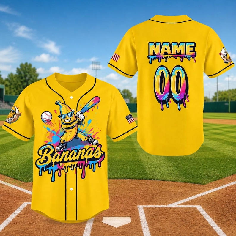 Pode incluir: Camisola de beisebol amarela com acabamento preto, com um personagem de banana de desenho animado com &oacute;culos de sol e um taco de beisebol. A frente diz "Bananas" em uma fonte colorida gotejante. A parte de tr&aacute;s tem "NAME" e "00".