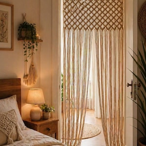 Può includere: Tenda per porta in macramè beige con motivo a rombi e fili verticali. La stanza ha un'atmosfera bohémien, con letto, comodino e piante. La tenda aggiunge un elemento naturale e strutturato all'ambiente.