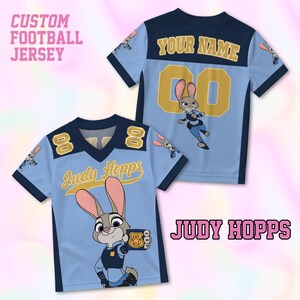 May include: Light blue custom football jersey featuring the character Judy Hopps from Zootopia. The jersey has navy blue accents, the number 8, and the name "Judy Hopps" in a yellow script. The back of the jersey has the number 00 and the text "YOUR NAME".