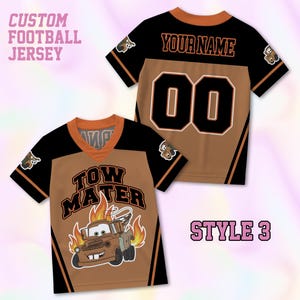 May include: Two short-sleeve football jerseys in black and brown. The front features the text TOW MATER above a cartoon tow truck graphic with flames. The back displays the text YOUR NAME and the number 00 in black with white outlines.