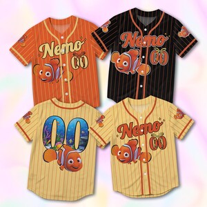 Könnte beinhalten: Vier kurzärmelige Baseballtrikots mit Knopfleiste, Nadelstreifen und dem Namen Nemo in Schreibschrift. Drei Trikots sind orange, schwarz und gelb mit einem Clownfisch-Motiv und der Nummer 00. Ein Trikot zeigt die Rückseite mit einer großen 00.