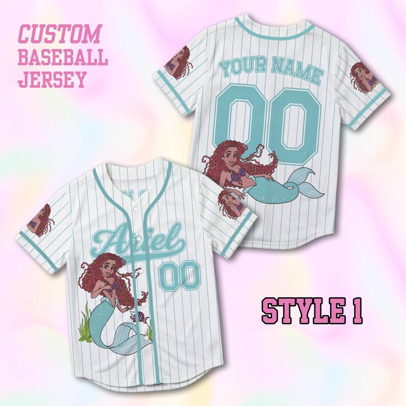 Puede incluir: Una camiseta de b&eacute;isbol blanca con rayas finas de color azul claro, con el texto Ariel y el n&uacute;mero 00 en la parte delantera, y el texto YOUR NAME y 00 en la parte trasera. La camiseta muestra un gr&aacute;fico de una sirena de pelo rojo.