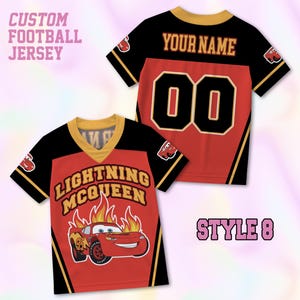 May include: A custom football jersey featuring a red and black design with gold trim. The front displays Lightning McQueen with flames and text. The back shows the text YOUR NAME and the number 00. The text CUSTOM FOOTBALL JERSEY and STYLE 8 appear.