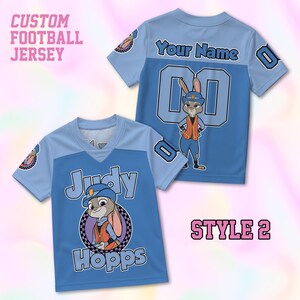 May include: Two light and medium blue custom football jerseys featuring a graphic of Judy Hopps in a police uniform. The front displays the name Judy Hopps, while the back includes the text Your Name and the number 00. Both shirts have short sleeves.