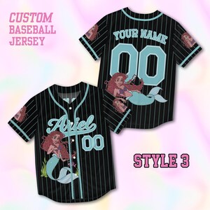 Puede incluir: Una camiseta de b&eacute;isbol negra con finas rayas verticales de color azul claro, con el texto CUSTOM BASEBALL JERSEY y STYLE 3. El frente muestra el nombre Ariel y el n&uacute;mero 00, mientras que la parte posterior muestra YOUR NAME y 00, con gr&aacute;ficos de sirena.