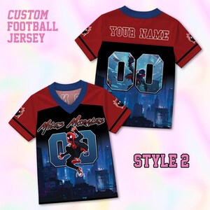 May include: A custom football jersey featuring a red and black design with a city skyline graphic. The front displays the text Miles Morales and the number 00. The back shows the text Your Name and the number 00. The jersey has a blue V-neck collar.