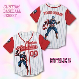 May include: A white baseball jersey with red sleeves and blue pinstripes featuring a Captain America graphic, the text Captain America, and the number 00 on the front. The back displays the text YOUR NAME and a Captain America graphic.