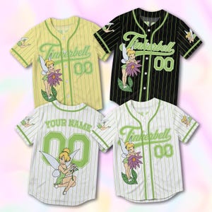 Puede incluir: Cuatro camisetas de béisbol abotonadas con gráficos de Campanilla. Una es amarilla con rayas verdes, una es negra con rayas verdes y dos son blancas con rayas verdes. Cada camisa muestra el texto Tinkerbell y el número 00.