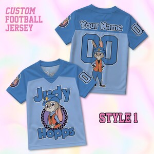 May include: A light blue football jersey featuring a graphic of Judy Hopps in a police uniform. The front displays the text Judy Hopps, while the back shows the text Your Name above the number 00. The sleeves feature a checkered pattern.
