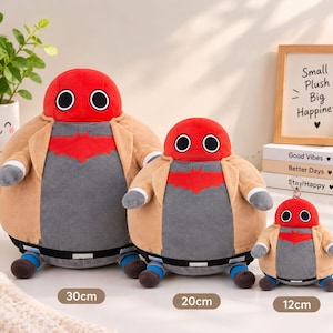 May include: Three plush toys in sizes 30cm, 20cm, and 12cm. Each features a red head with black-rimmed white eyes, a grey torso with a red bat-like emblem, a tan jacket, grey sleeves, a black belt, and blue feet. The toys have a round, soft body shape.