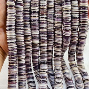 May include: Multiple strands of flat, circular disc-shaped beads featuring a marbled pattern of deep purple, lavender, and white. Each bead has a smooth, polished finish with a central hole, arranged in long, vertical, parallel rows.