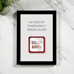 Może przedstawiać: Oprawiony wydruk z czarną obwódką. Wydruk zawiera tekst "IN CASE OF EMERGENCY BREAK GLASS" nad czerwonym i srebrnym przyciskiem z tekstem "IDDQD IDKFA". Tło jest jasne.