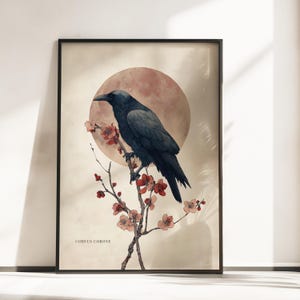 Könnte beinhalten: Ein gerahmter Kunstdruck mit einem dunkelblau-schwarzen Raben, der auf einem dünnen Zweig mit kleinen roten Blüten sitzt. Hinter dem Vogel befindet sich ein großer, rötlich-brauner kreisförmiger Mond. Der Text CORVUS CORONE steht unten links.