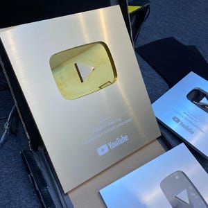 May include: Gold and silver YouTube Play Buttons. The gold plaque is engraved with "Presented to Mahasin Gaming For passing 1,000,000 subscribers" and the YouTube logo. The silver plaques are engraved with the YouTube logo and text.