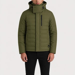 Peut inclure: Veste matelassée vert olive avec capuche et fermeture éclair noire. La veste a un col montant et un petit détail d'anneau noir en bas à droite. Le modèle porte un pantalon noir.