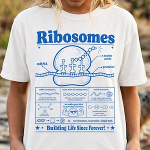 Könnte beinhalten: Weißes T-Shirt mit einem blauen Grafikdesign mit dem Wort "Ribosomen" und wissenschaftlichen Diagrammen. Das Design enthält Text über mRNA, Aminosäuren und Proteinsynthese. Der Satz "Building Life Since Forever!" ist ebenfalls enthalten.