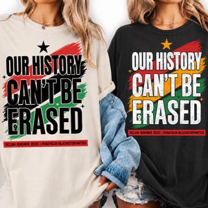Könnte beinhalten: Zwei T-Shirts, eines in Creme und eines in Schwarz, mit dem Text "OUR HISTORY CAN'T BE ERASED" in fetter Schrift. Das Design enthält einen Pinselstrich-Hintergrund in Rot, Gelb und Grün, einen Stern und den Text "RECLAIM. REMEMBER. RESIST."