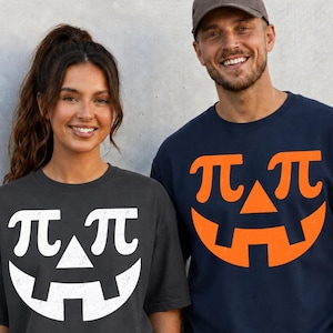May include: A dark gray t-shirt with a white graphic of a jack-o'-lantern face where the eyes are pi symbols, and a navy blue t-shirt with an orange graphic of a jack-o'-lantern face where the eyes are pi symbols, both featuring a triangular nose.