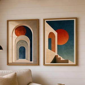 May include: Two framed wall art prints featuring architectural archways and a large red sun against a deep blue sky. The left print shows a series of receding arches, while the right print depicts a staircase leading toward a bright red sun.