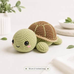 Puede incluir: Un juguete de tortuga tejido a ganchillo con cabeza y cuerpo de color verde claro, caparazón marrón, ojos de plástico negro y pequeñas mejillas rosadas bordadas. La tortuga mide 18 cm de largo, según la etiqueta en la parte inferior.