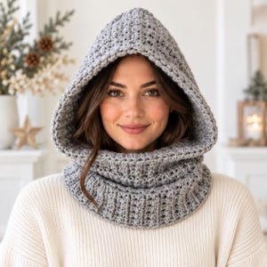 May include: A light grey crochet hooded cowl featuring a thick, textured knit pattern. The accessory covers the head with a pointed hood and wraps around the neck with a ribbed collar design, providing full coverage for the head and neck area.