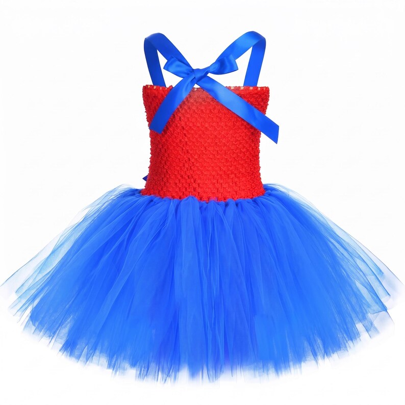 Op de afbeelding: Een mouwloze jurk met een felrood gehaakt lijfje en een volumineuze blauwe tule rok. Het lijfje is geaccentueerd met felblauwe satijnen lintbandjes die op de rug kruisen en in een strik worden vastgemaakt, wat een opvallend contrast cre&euml;ert.