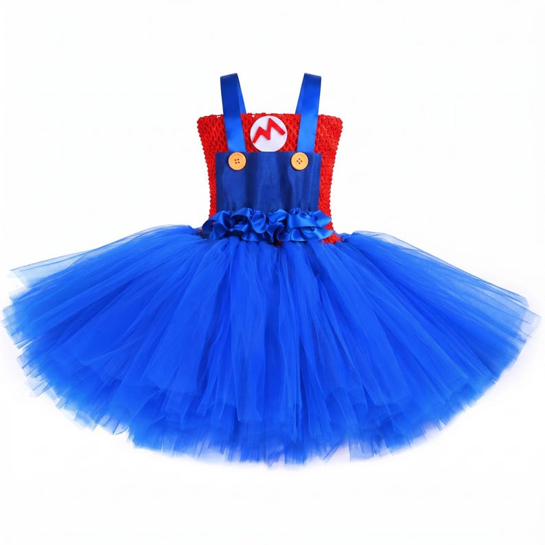Op de afbeelding: Een mouwloze jurk met een rood gehaakt lijfje en een witte ronde patch met een rode letter M. De jurk is voorzien van blauwe satijnen bandjes, twee gele knopen en een volumineuze, gelaagde blauwe tule rok met ruches.