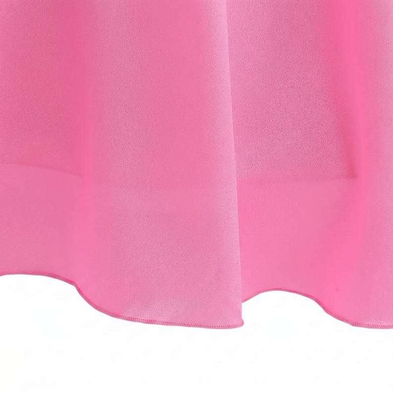 May include: Close-up of a vibrant pink fabric, possibly a dress or skirt, with soft folds and a delicate hemline. The material appears smooth and lightweight, with a subtle sheen. The bright color dominates the frame.