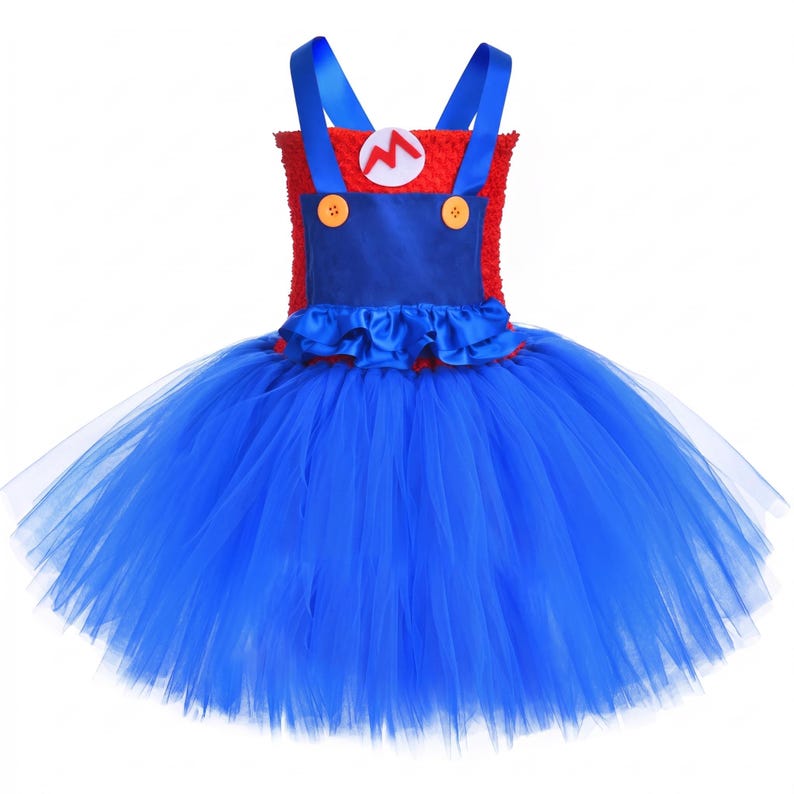 Op de afbeelding: Een mouwloze jurk met een rood, getextureerd lijfje en een witte, ronde patch met een rode letter M. De jurk heeft blauwe satijnen schouderbandjes, een blauw voorpand met twee gele knopen en een volumineuze blauwe tule rok.