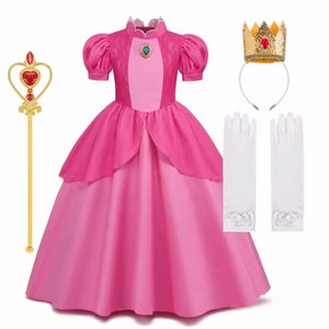 May include: A pink princess costume set, including a long gown, crown, gloves, and a scepter. The dress features a layered skirt and puffed sleeves. The gold crown has red accents, and the scepter has a heart-shaped jewel.