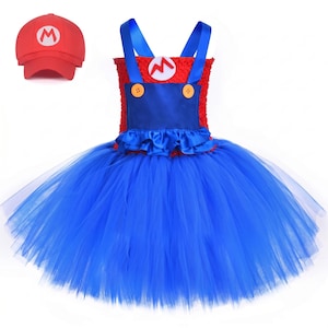 Op de afbeelding: Een rood en blauw tutu-jurkje met een textuurrijk rood lijfje, een blauw satijnachtig paneel met twee gele knopen, blauwe schouderbandjes en een volle blauwe tule rok. Een rode baseballpet met een witte cirkel en rode letter M is inbegrepen.