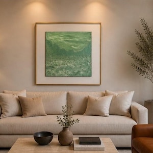 May include: A living room scene featuring a beige sofa with several pillows, a wooden floor lamp, and a framed abstract green painting. A brown leather armchair and a potted plant are also visible.