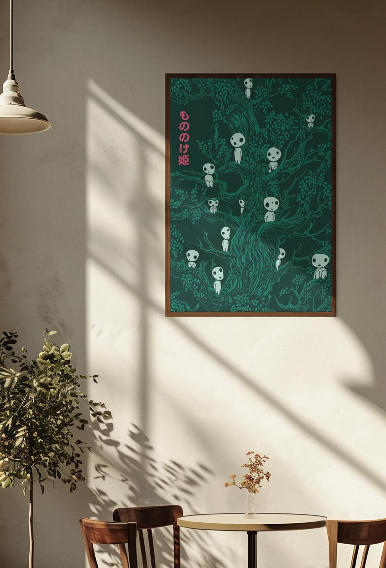May include: A framed poster featuring a dark green illustration of a tree with numerous white spirit-like figures. The Japanese text "もののけ姫" is in pink on the left side. The artwork is displayed on a white wall.