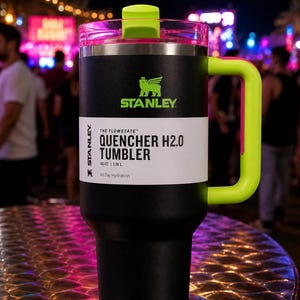 Pu&ograve; includere: Bicchiere Stanley Quencher H2.0 nero e verde neon. Il bicchiere ha un corpo nero con manico, coperchio e cannuccia verde neon. Il testo "STANLEY" e "QUENCHER H2.0 TUMBLER" sono stampati. Capacit&agrave;: 1,18 L.