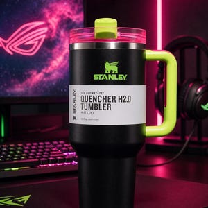 Pu&ograve; includere: Bicchiere Stanley Quencher H2.0 nero con manico e coperchio verde neon. Il bicchiere ha un'etichetta bianca con la scritta "QUENCHER H2.0 TUMBLER" e il logo Stanley. Il bicchiere &egrave; da 1,18 L.