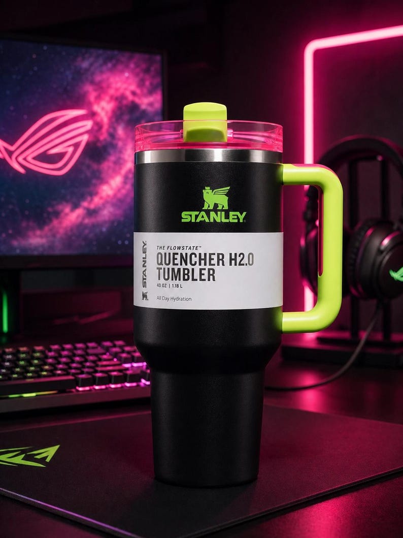 Pu&ograve; includere: Bicchiere Stanley Quencher H2.0 nero con manico e coperchio verde neon. Il bicchiere ha un'etichetta bianca con la scritta "QUENCHER H2.0 TUMBLER" e il logo Stanley. Il bicchiere &egrave; da 1,18 L.