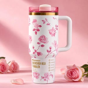 May include: White Stanley Quencher H2.0 tumbler with a pink floral pattern. The tumbler has a pink lid and handle, and the text "Stanley Quencher H2.0 Tumbler" is printed on the side. The tumbler holds 40 oz.