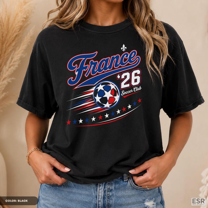 A woman wearing a black t-shirt with a graphic design featuring a soccer ball and stars, along with the text "France #26 Soccer Club".