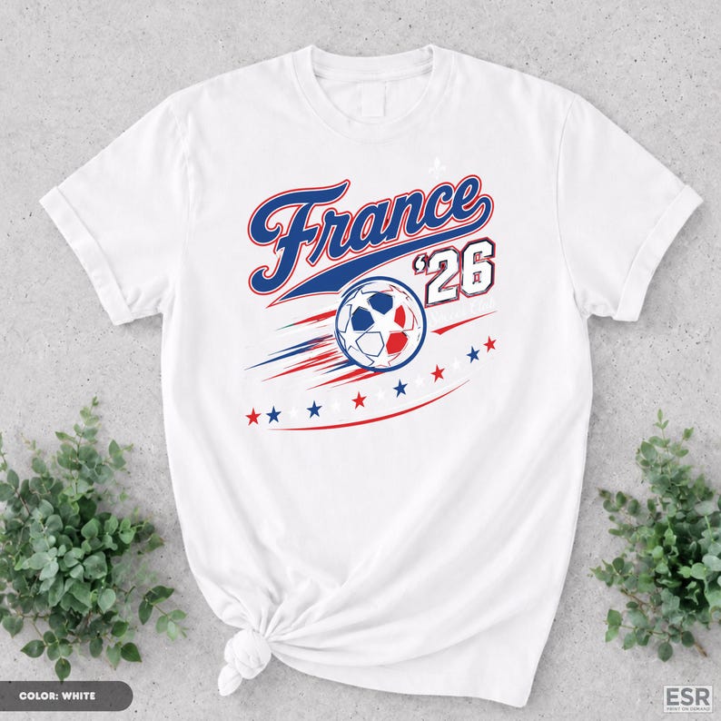 A white t-shirt with a graphic design featuring the text "France '26" and a soccer ball, surrounded by stars and stripes.