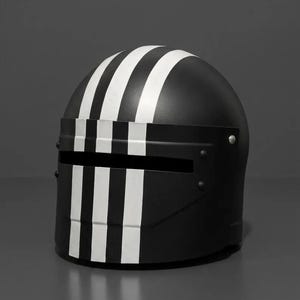 Puede incluir: Un casco negro mate con tres franjas blancas verticales que van desde la parte superior hasta la placa frontal. El casco incluye una abertura rectangular horizontal para la visera y está asegurado con remaches visibles en los laterales.