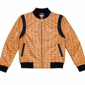 Puede incluir: Chaqueta bomber de color marrón claro con un patrón de logotipo negro repetido. La chaqueta presenta detalles negros en el cuello, los hombros y los puños, con cierre de cremallera completa y dos bolsillos delanteros. Prenda de vestir exterior elegante.