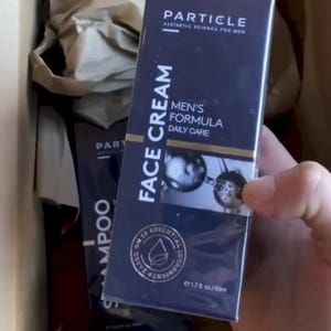 May include: A navy blue box of Particle Face Cream for men, with the text "Face Cream" and "Men's Formula Daily Care" in white. The box also includes the text "Particle Aesthetic Science for Men" and "On 12 Essential Ingredients". The product is 50ml.