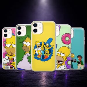 May include: Five smartphone cases featuring The Simpsons characters. One shows Homer eating a donut, another Homer in a bush, a yellow case with the family, one with Homer and donuts, and a teal case with Apu and Homer holding two guns.