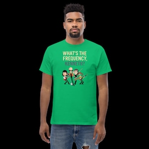 May include: Green t-shirt with the text "WHAT'S THE FREQUENCY, KENNETH?" above a cartoon band playing instruments. The band members are depicted in black and white, with one holding a microphone.