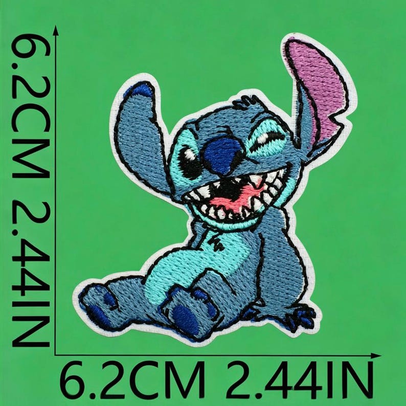 May include: An embroidered patch featuring a blue alien character with large ears, a wide grin, and sharp teeth. The patch measures 6.2 cm or 2.44 inches in height and width, as indicated by the black measurement lines printed on the image.