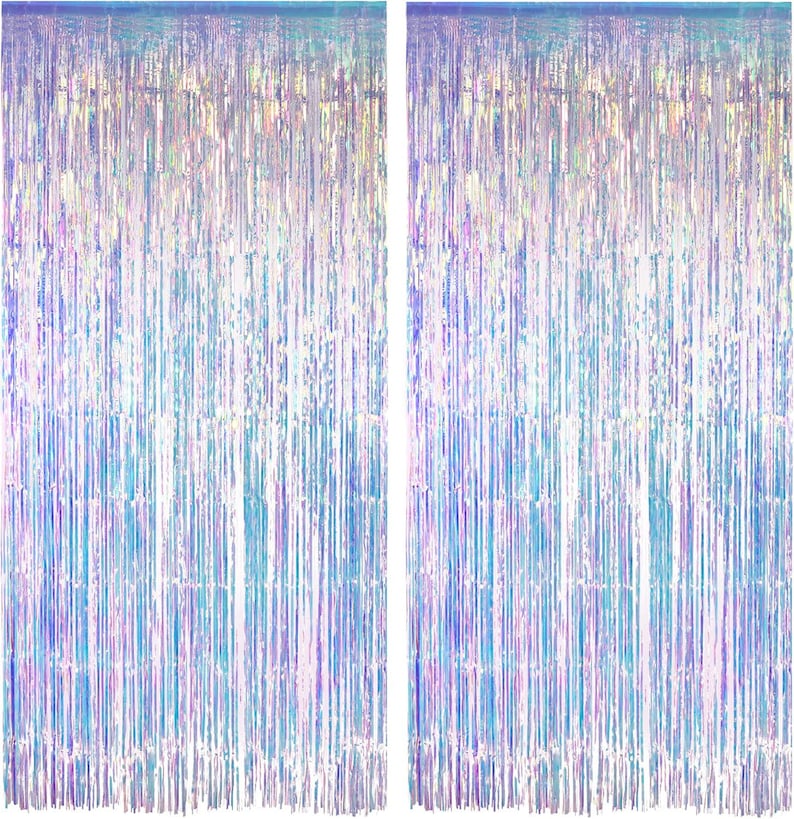 May include: Two rectangular fringe curtains featuring a vertical, thin-strip design. The material has an iridescent, holographic finish that reflects light, displaying a spectrum of shifting colors including light blue, pink, and silver tones.
