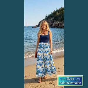 May include: A navy blue sleeveless tank top paired with a floor-length, wide-leg skirt featuring a white, blue, and yellow nautical print of sailboats and waves. The skirt has a drawstring waist and a loose, flowing silhouette.