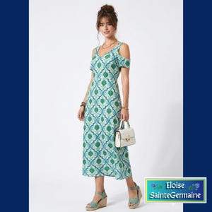 May include: A woman in a green and blue patterned dress with cold shoulder sleeves, wedge sandals, and a white handbag. The dress features a V-neck and a knee-length hem. The dress has a floral pattern. The text "Eloise SainteGermaine" is visible.