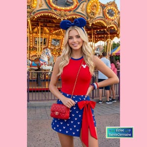 Op de afbeelding: Een mouwloze rode top met een wit Mickey Mouse-icoon, gecombineerd met een blauwe overslagrok met een wit Mickey Mouse-patroon en een grote rode strik. Een rode gewatteerde schoudertas met een gouden ketting en een muizenoor-haarband.