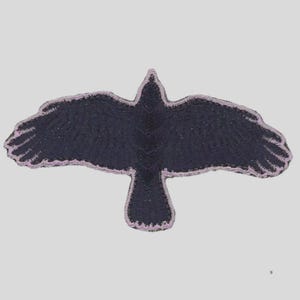 May include: A black crow patch with outstretched wings, embroidered with a textured appearance. The patch is outlined with a light purple stitching, creating a contrasting border. The crow design is centered on a light gray background.
